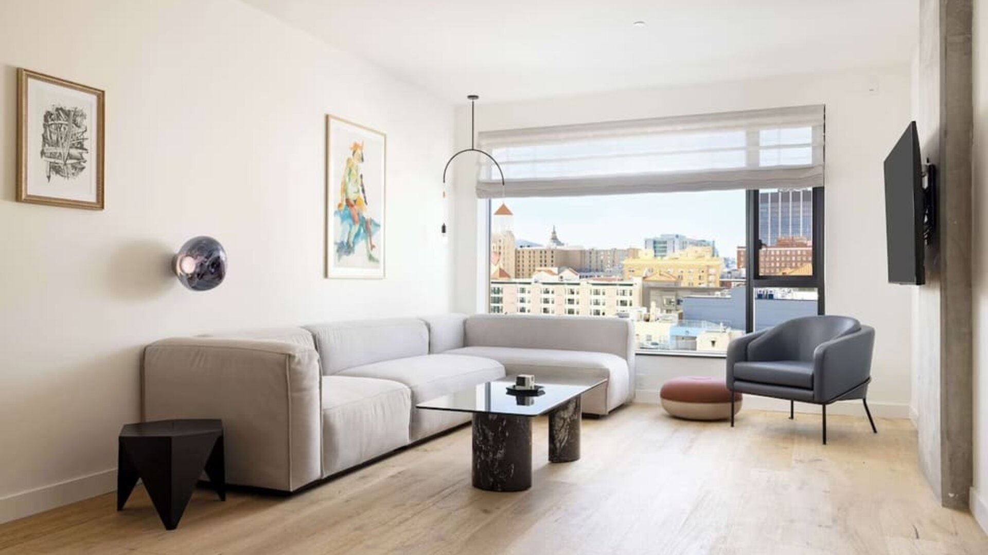 Living area with sofa, armchair, and city views through large windows at Timbri Hotel San Francisco, Curio Collection By Hilton.