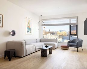 Living area with sofa, armchair, and city views through large windows at Timbri Hotel San Francisco, Curio Collection By Hilton.