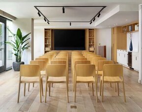 Meeting room set up in theatre style with wooden chairs and presentation screen at Timbri Hotel San Francisco, Curio Collection By Hilton.