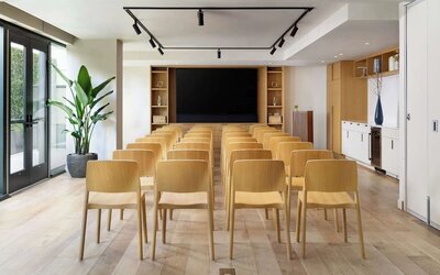 Meeting room set up in theatre style with wooden chairs and presentation screen at Timbri Hotel San Francisco, Curio Collection By Hilton.