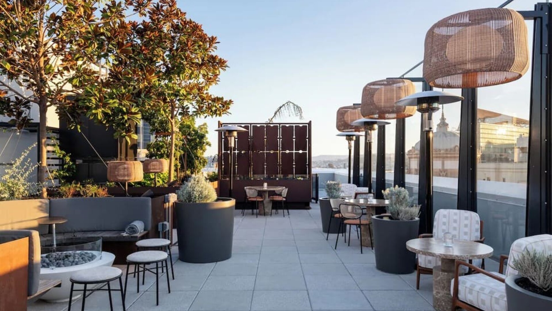 Outdoor terrace dining area with plants, seating, and city skyline views at Timbri Hotel San Francisco, Curio Collection By Hilton