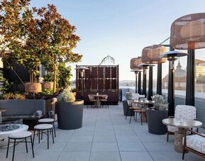 Outdoor terrace dining area with plants, seating, and city skyline views at Timbri Hotel San Francisco, Curio Collection By Hilton