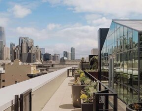 Rooftop terrace with planters, seating, and panoramic city views at Timbri Hotel San Francisco, Curio Collection By Hilton.