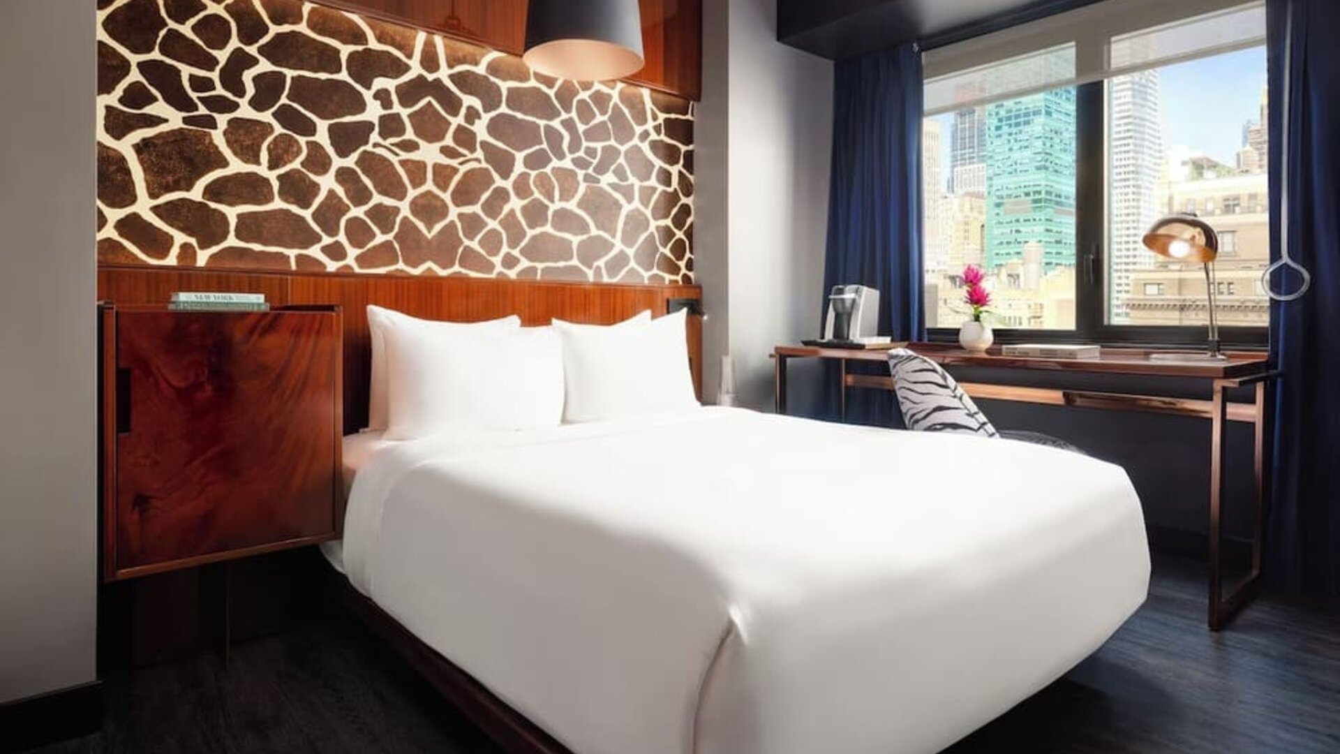 Stylish guest room with king bed, desk workspace, city views, and decorative feature wall at Hotel Hendricks.