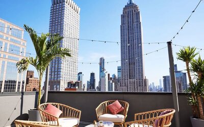 Rooftop terrace with seating, string lights, and skyline views including the Empire State Building at Hotel Hendricks.