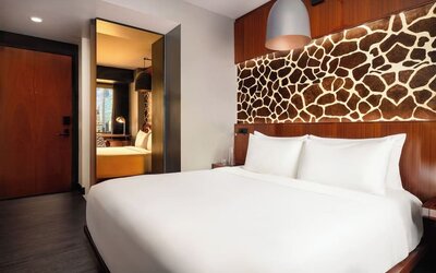 Guest room with large bed, decorative wall panel, and sleek interior design at Hotel Hendricks.