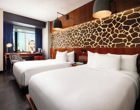 Double room with two beds, feature wall design, and workspace by the window at Hotel Hendricks.