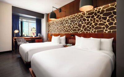 Double room with two beds, feature wall design, and workspace by the window at Hotel Hendricks.