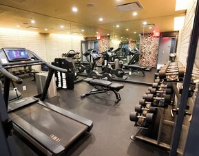 Fitness center with treadmills, weights, and mirrored walls at Hotel Hendricks.