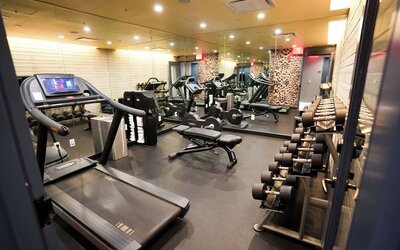 Fitness center with treadmills, weights, and mirrored walls at Hotel Hendricks.