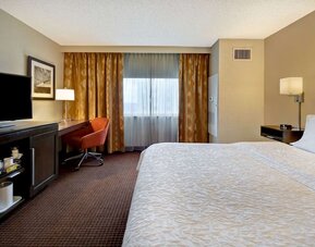 Simple King Bedroom with TV, work station, and natural light at Hampton Inn NY-JFK.