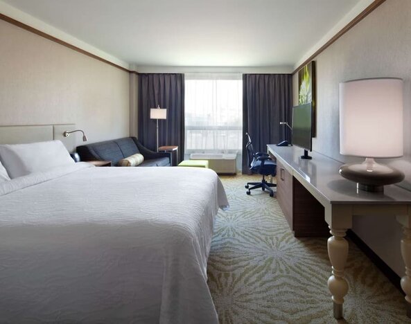 day use room with table, lamp shade, and work station at Hilton Garden Inn Montreal Airport.