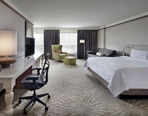 King bedroom with work desk and work chair and TV at Hilton Garden Inn Montreal Airport.