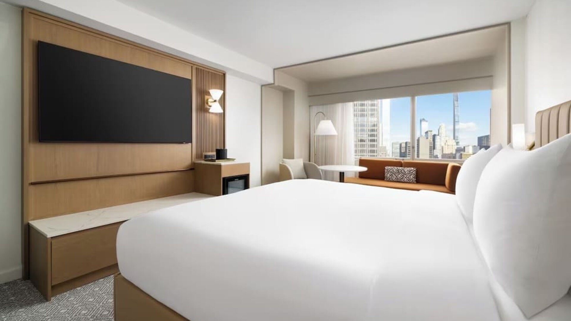 King room with large bed, seating area, and city skyline views at Hyatt Regency Times Square.