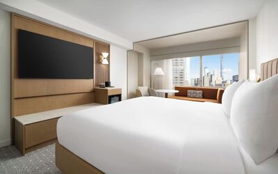 King room with large bed, seating area, and city skyline views at Hyatt Regency Times Square.