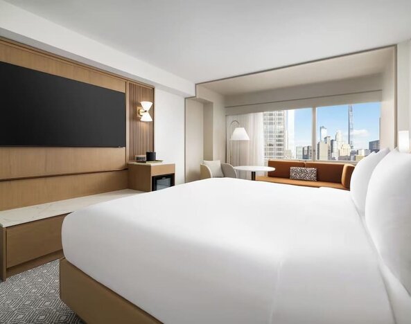 King room with large bed, seating area, and city skyline views at Hyatt Regency Times Square.