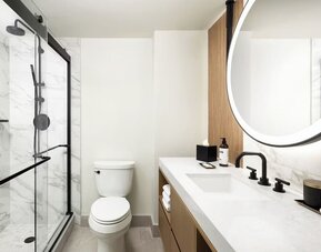Modern bathroom with glass-enclosed shower, marble walls, and vanity at Hyatt Regency Times Square.