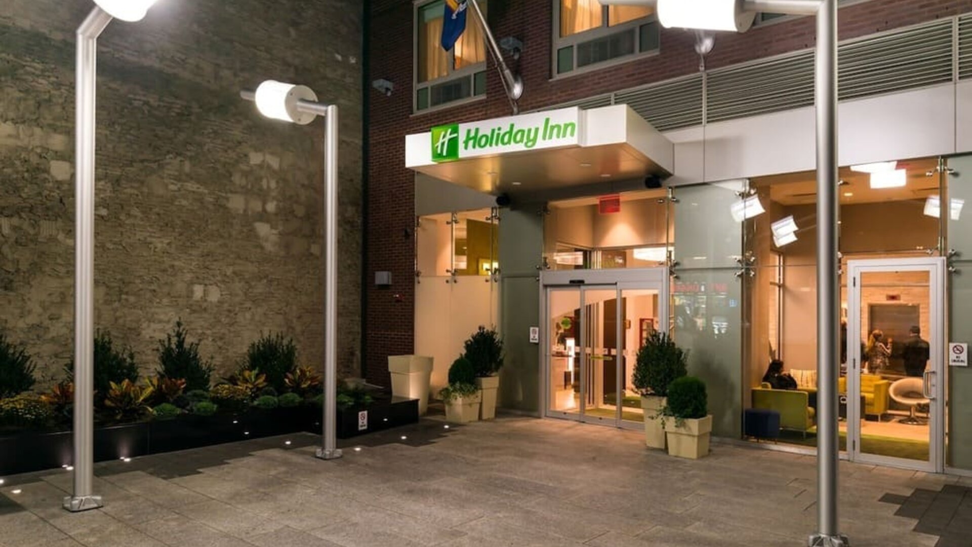 Hotel front entrance with illuminated signage and glass doors at Holiday Inn New York City - Times Square By IHG.
