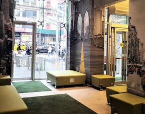 Lobby seating area with modern décor, wall art, and glass entrance at Holiday Inn New York City - Times Square By IHG.