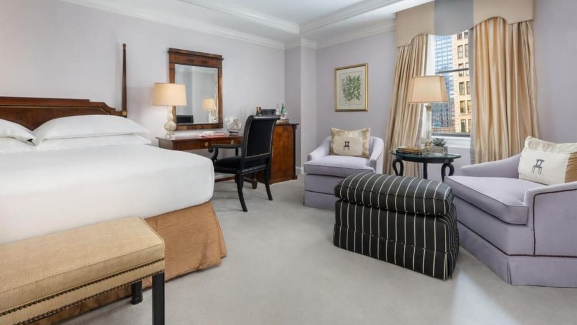 Classic guest room with plush bedding, writing desk, and elegant seating area at The Michelangelo New York.