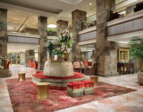 Grand lobby with marble floors, decorative columns, and floral centerpiece at The Michelangelo New York.