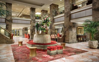 Grand lobby with marble floors, decorative columns, and floral centerpiece at The Michelangelo New York.