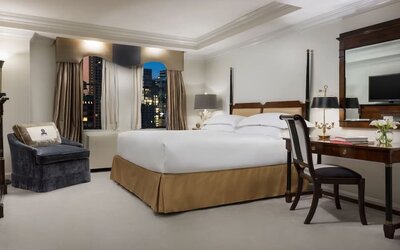 King bedroom with warm tones, desk area, and refined classic styling at The Michelangelo New York.