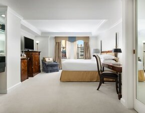 Spacious suite with separate living area, desk workspace, and city views at The Michelangelo New York.