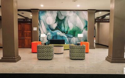 Lobby seating area with modern chairs, decorative wall art, and open layout at Wyndham Garden Williamsburg Busch Gardens Area.