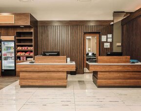 Reception desk area with wood finishes, snack station, and front desk service area at Wyndham Garden Williamsburg Busch Gardens Area.