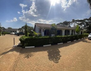 Wide view of the lodge grounds showing multiple units, landscaped hedges, and parking area under a clear sky at Sega Lodge.