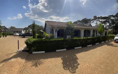 Wide view of the lodge grounds showing multiple units, landscaped hedges, and parking area under a clear sky at Sega Lodge.