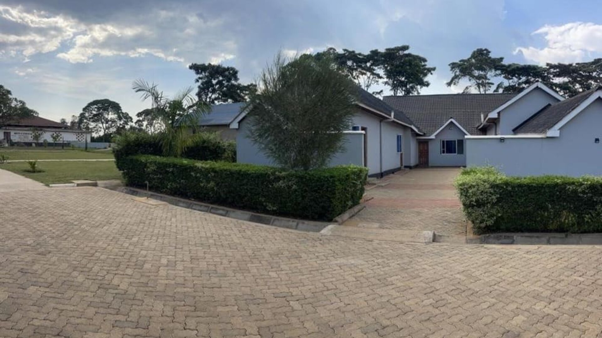 Pathway leading to lodge units bordered by trimmed hedges and greenery within the Sega Lodge property.