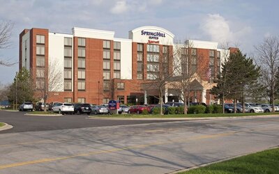 Exterior view of Marriott SpringHill Suites Naperville/Warrenville with red brick facade, covered entrance, and parked cars.