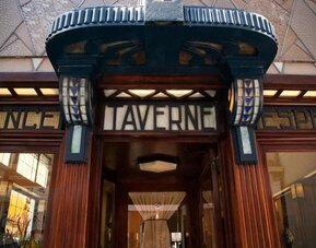 Decorative entrance with ornate wood framing and illuminated signage above glass doorway at Hôtel Espérance.