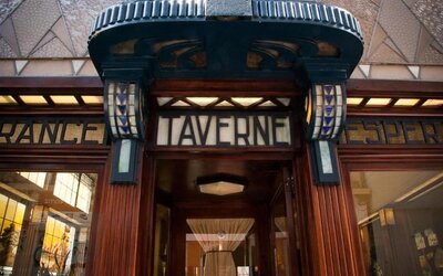 Decorative entrance with ornate wood framing and illuminated signage above glass doorway at Hôtel Espérance.