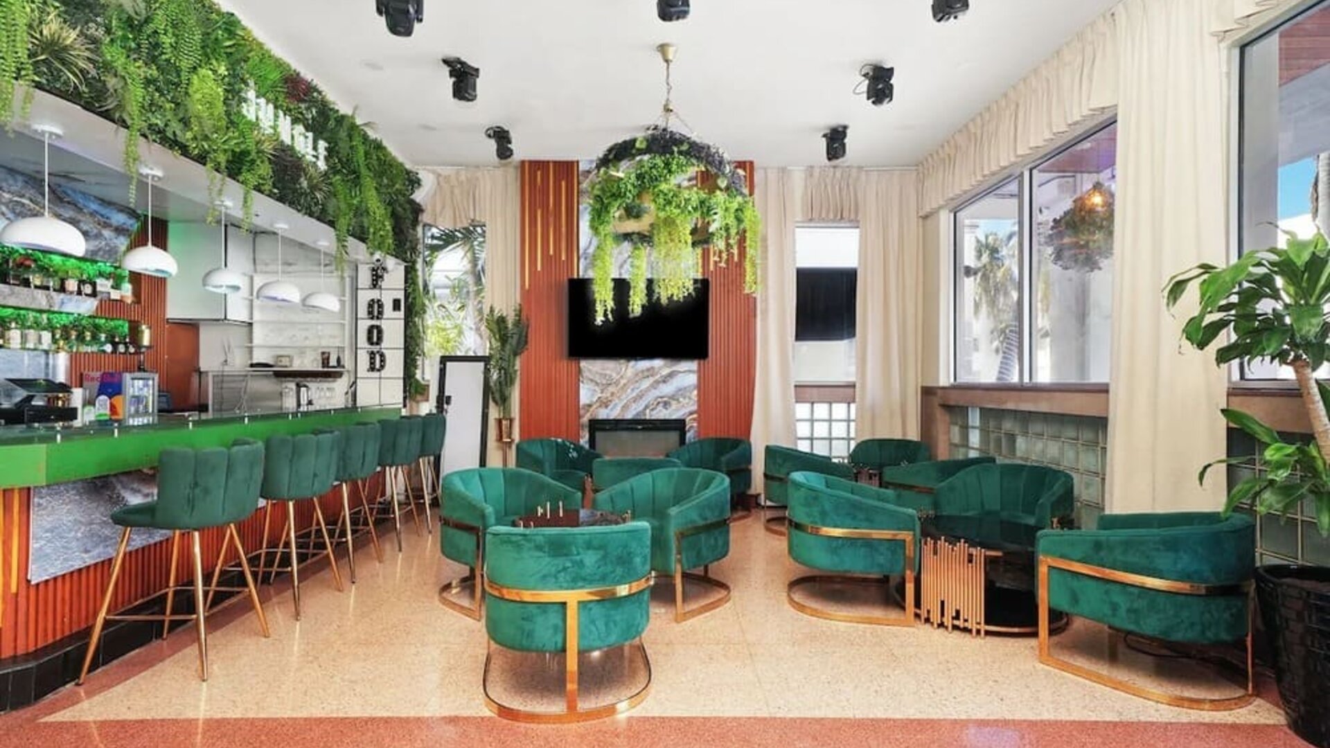 Modern lounge bar with green seating, pendant lights, marble feature wall, and indoor plants at Chesterfield Hotel & Suites.