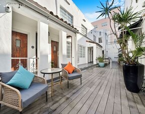 Outdoor courtyard with white buildings, wooden deck, seating areas, and potted plants at Chesterfield Hotel & Suites.