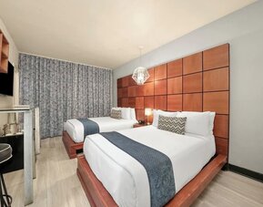Double bed room with wood headboards, gray runners, workspace, and floor-length curtains at Chesterfield Hotel & Suites.