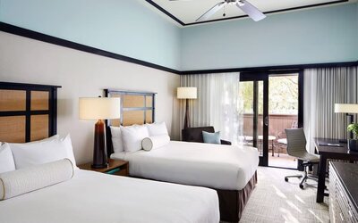 Guest room with two beds, work desk, balcony access, and neutral-toned decor at The Ambrose Hotel Santa Monica.