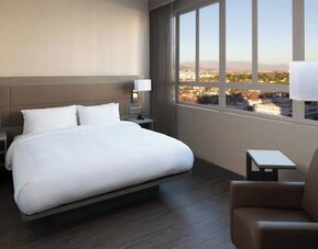 Guest room with king bed, floor-to-ceiling windows, city views, and modern furnishings at AC Hotel By Marriott Beverly Hills.