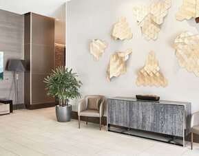 Lobby seating area with geometric wall art, potted plants, and contemporary furniture at AC Hotel By Marriott Beverly Hills.