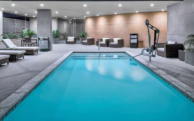 Indoor pool area with seating, accessibility lift, and ambient lighting at Hampton Inn & Suites Los Angeles / Hollywood.