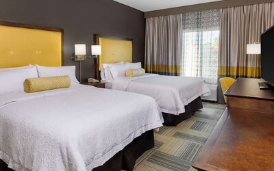 Guest room with two beds, yellow headboards, window seating, and coordinated décor at Hampton Inn & Suites Los Angeles / Hollywood.