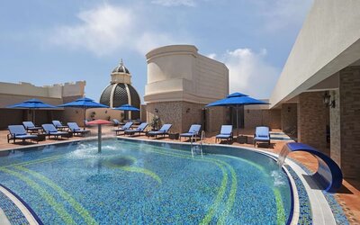 Outdoor pool with blue loungers, umbrellas, water features, and surrounding terrace seating