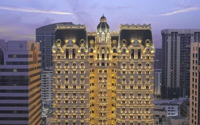 Illuminated multi-story hotel exterior at dusk with ornate façade and surrounding city buildings