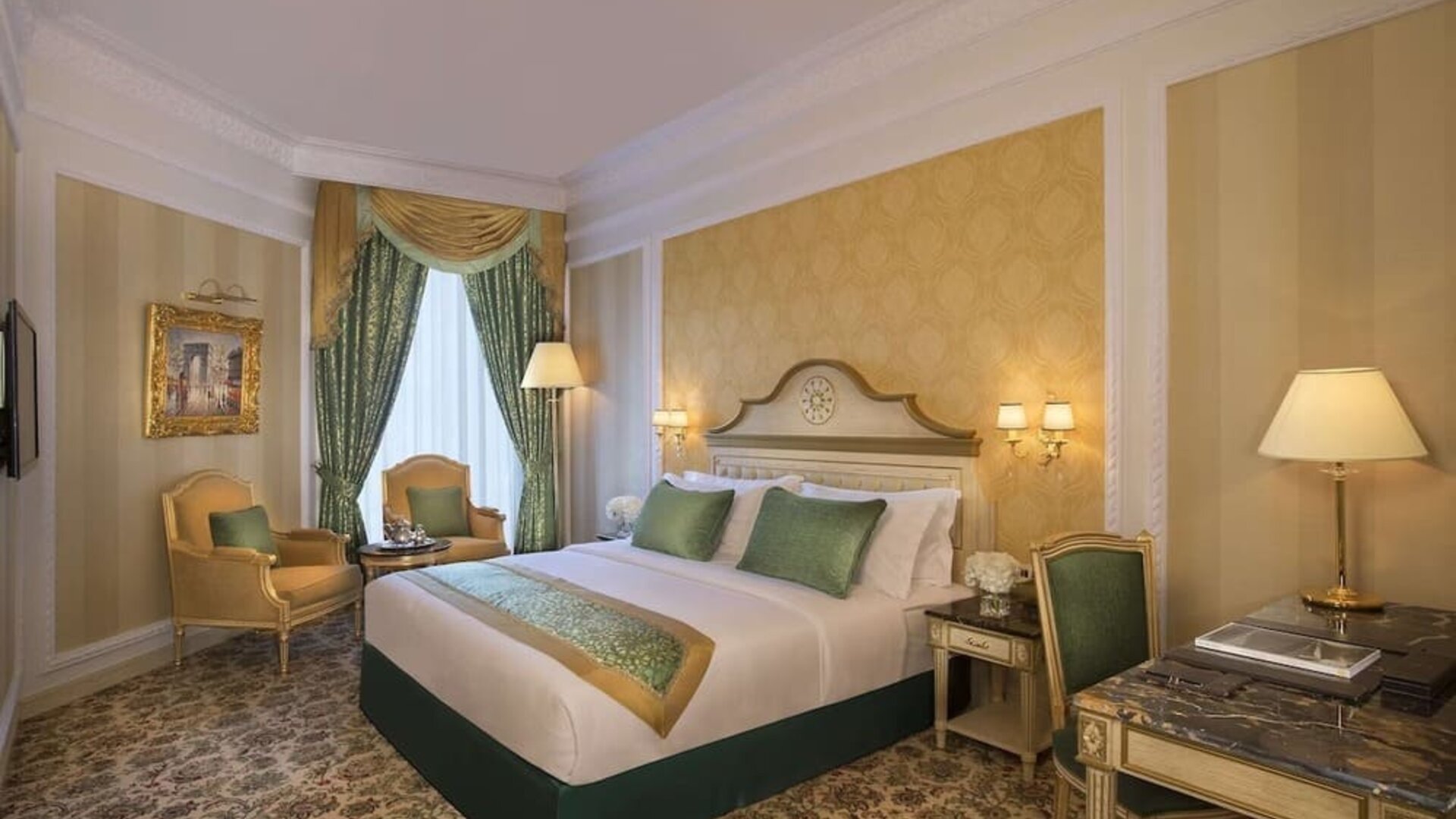 Classic king room with patterned carpet, armchair seating area, and desk beneath large mirror