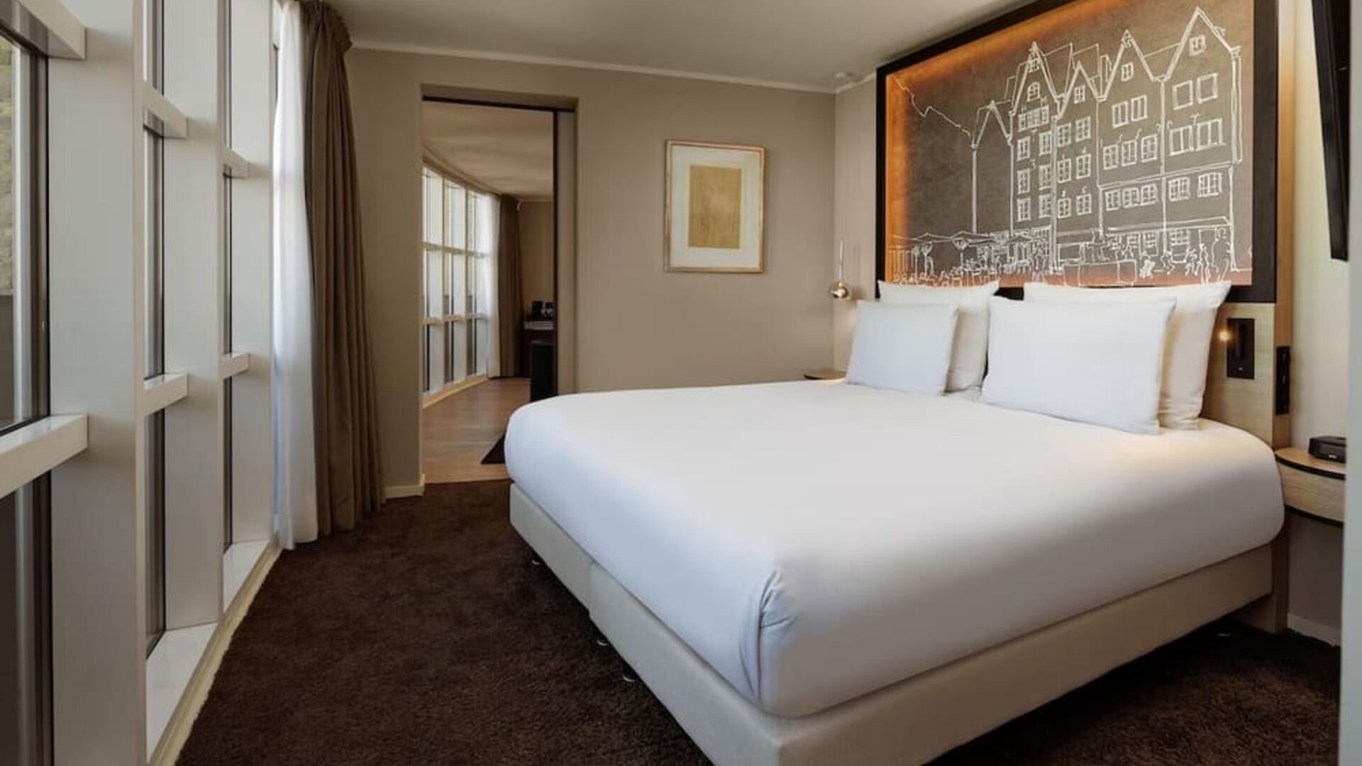 King room with large bed, decorative headboard, and wide window with city-facing view