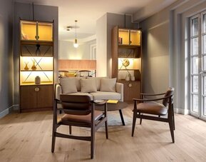 Lounge area with sofa, armchairs, coffee table, and built-in shelves with warm accent lighting