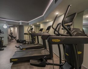 Compact fitness room with treadmills, elliptical machines, mirrors, and overhead recessed lighting